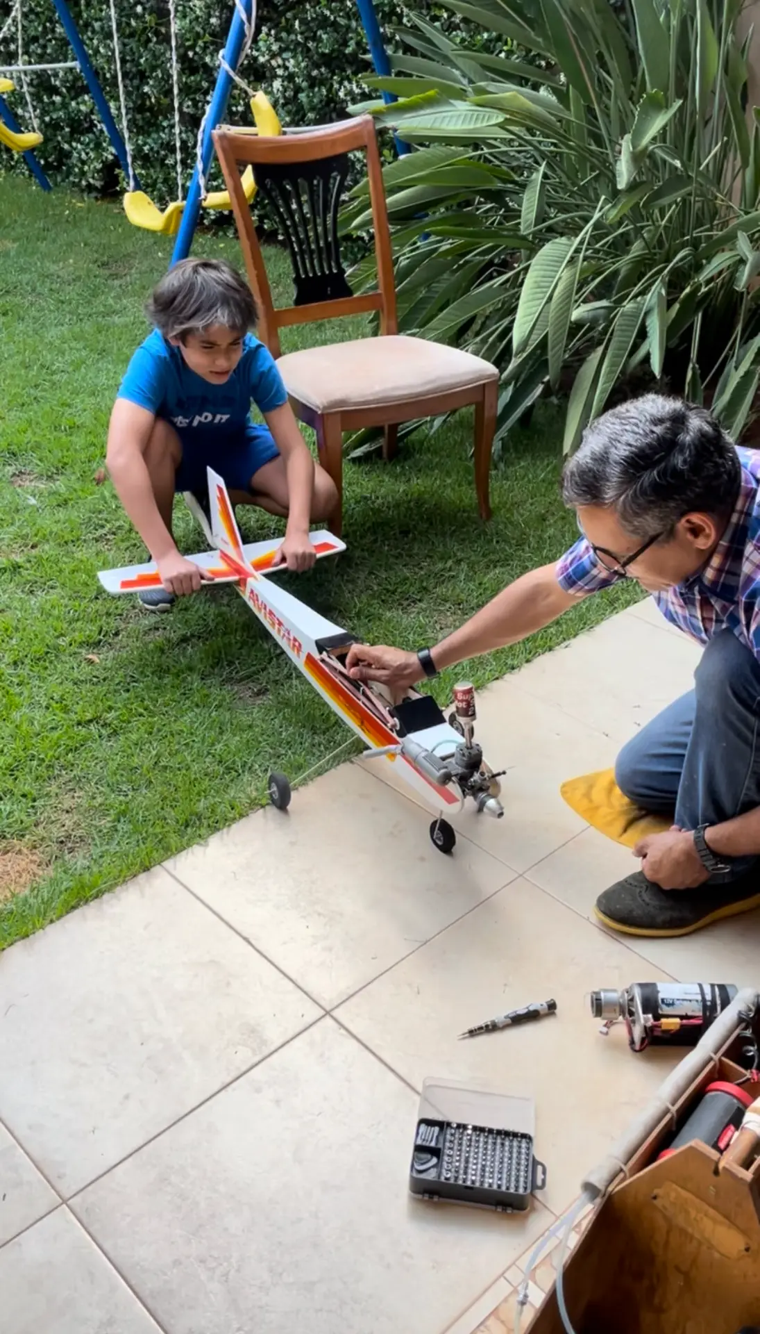Niño y su profe preparando juntos el aeromodelo a combustión en el patio